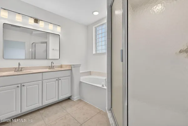 a spacious bathroom with a double vanity sink a mirror and a bathtub