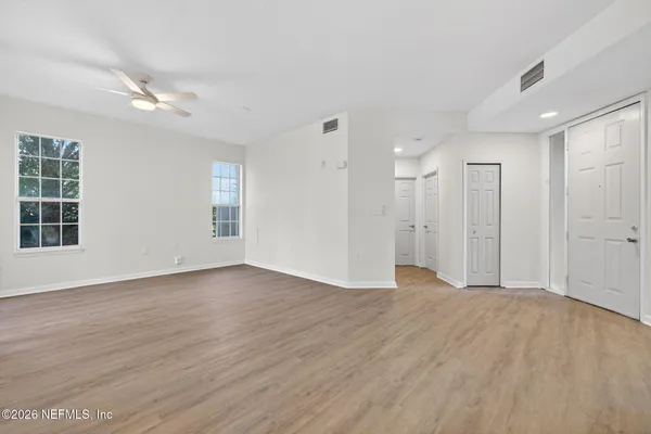 a view of an empty room with wooden floor and a window
