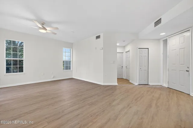 a view of an empty room with wooden floor and a window
