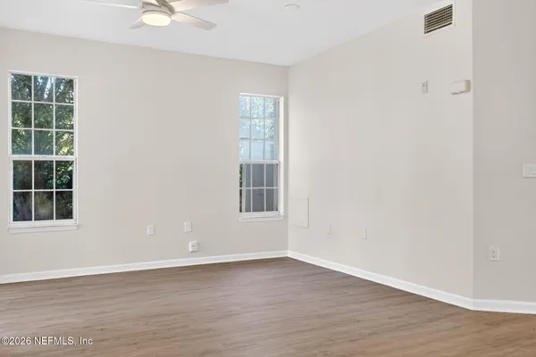 an empty room with wooden floor and windows