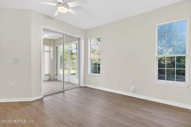 an empty room with wooden floor and windows
