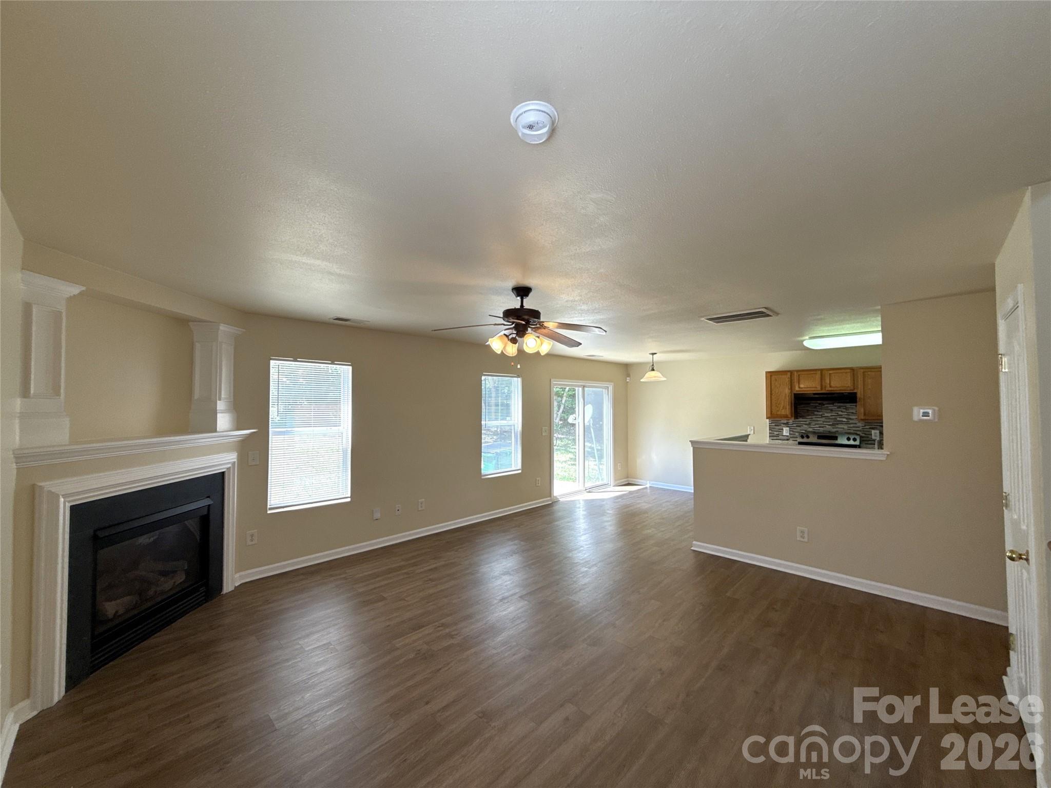 6831 Sunman Road Charlotte, NC 28216 - Photo 3 of 14 an empty room with fireplace wooden floor and windows