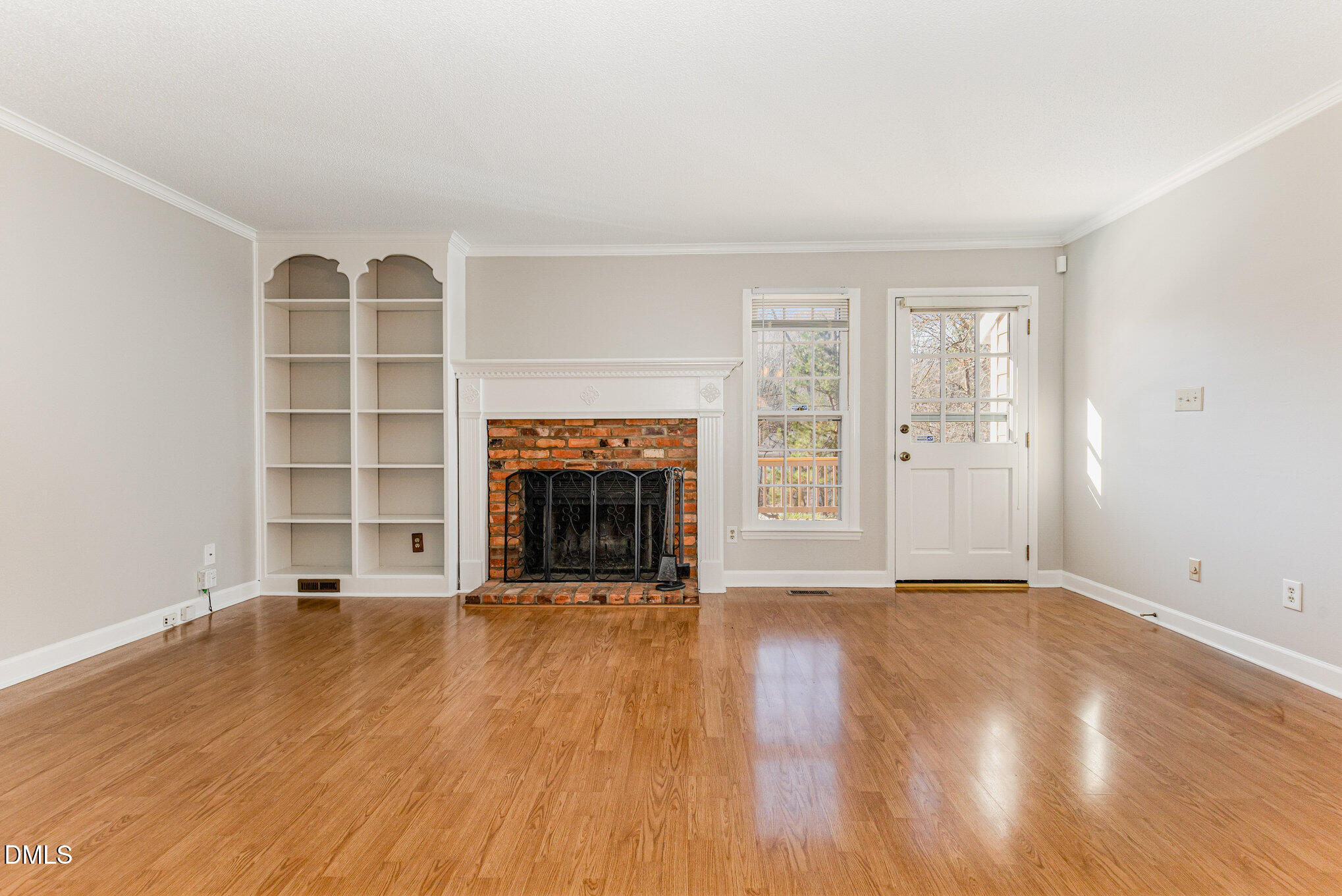 4534 Hamptonshire Drive Raleigh, NC 27613 - Photo 3 of 27 a view of an empty room with wooden floor fireplace and a window