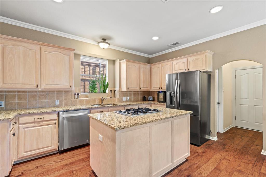 3710 Sam Rayburn Trail Dallas, TX 75287 - Photo 14 of 36 a kitchen with a stove a sink a refrigerator and white cabinets with wooden floor