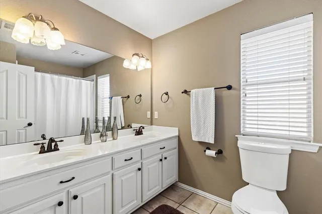 a bathroom with a double vanity sink mirror and toilet