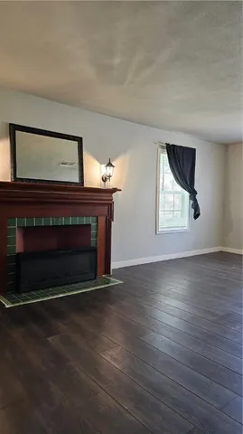 an empty room with wooden floor fireplace and windows