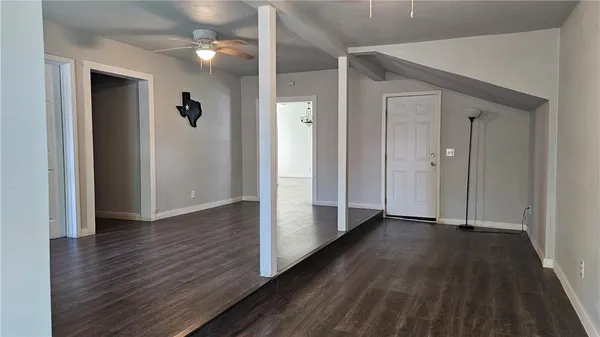 an empty room with wooden floor closet and windows