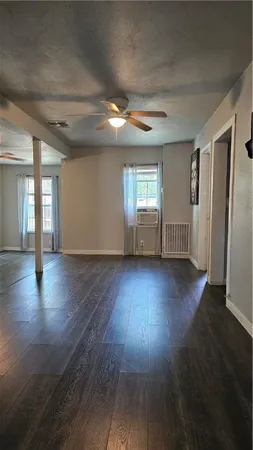 an empty room with wooden floor and windows with curtains