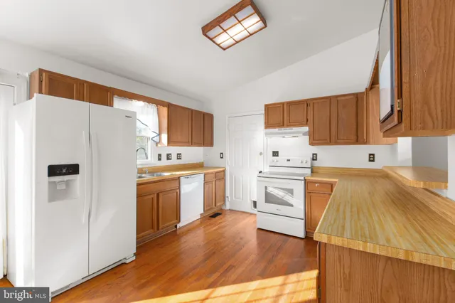 a kitchen with granite countertop a refrigerator stove top oven and sink