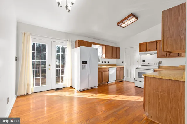 a kitchen with stainless steel appliances wooden floor and a refrigerator