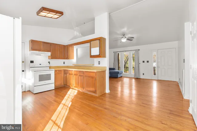 a large kitchen with stainless steel appliances a stove a sink dishwasher and a refrigerator with wooden floor