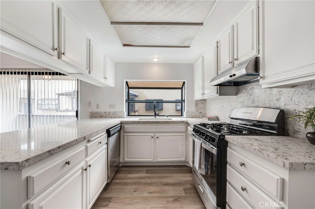 a kitchen with stainless steel appliances granite countertop a sink stove cabinets and a window
