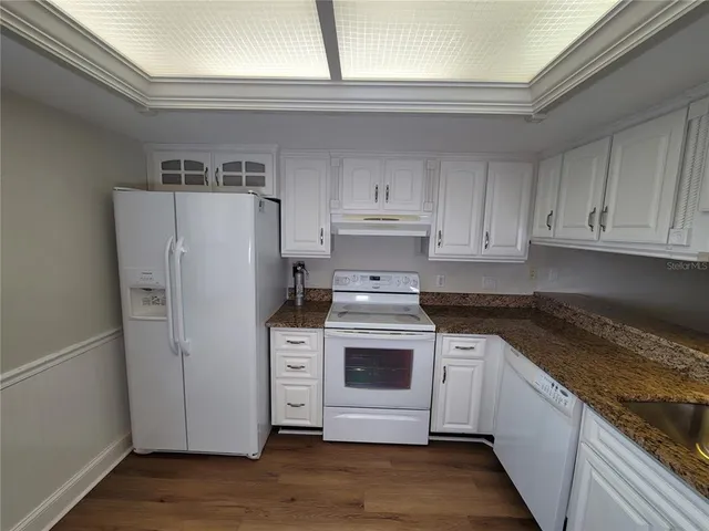 a kitchen with granite countertop white cabinets and a sink