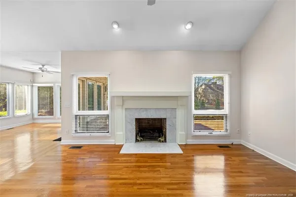 a view of an empty room with wooden floor fireplace and a window