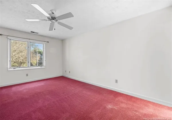 an empty room with a window and a ceiling fan