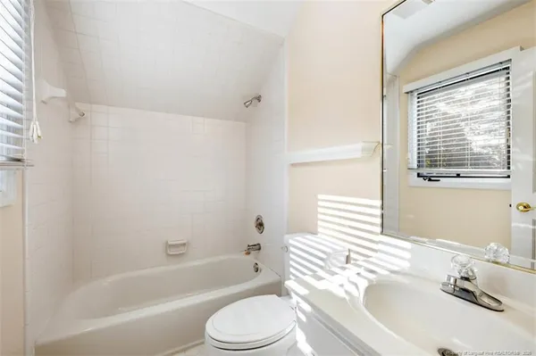 a bathroom with a bathtub shower sink vanity mirror and a toilet