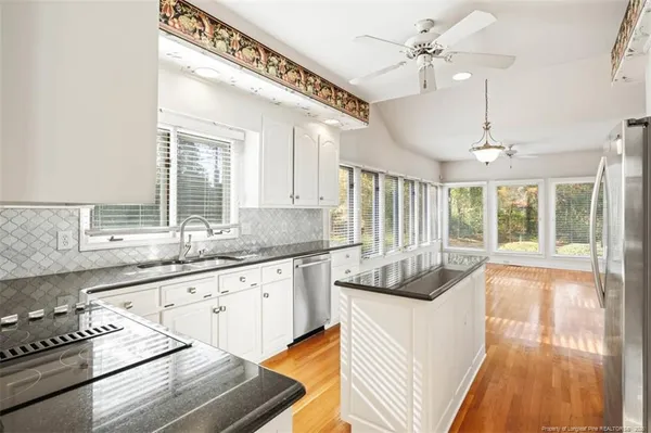 a kitchen with granite countertop a stove and white cabinets