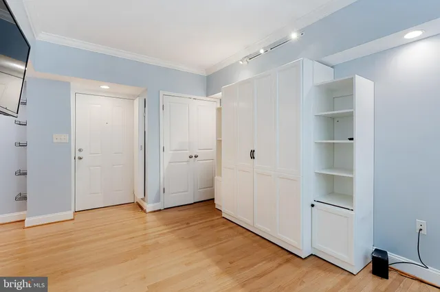 a view of an empty room with wooden floor and closet