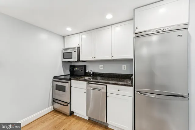 a kitchen with granite countertop a refrigerator and a stove top oven