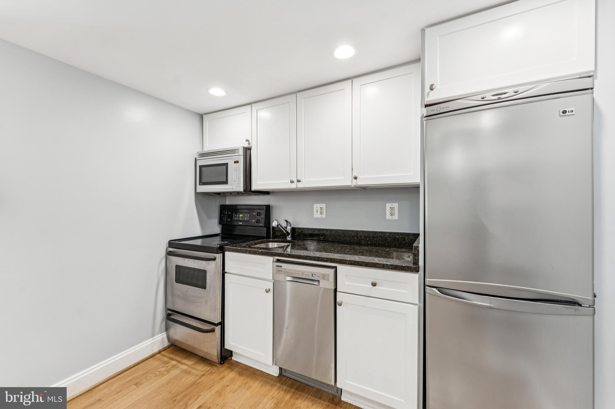 1701 16th Street Northwest, Unit 304 Washington, DC 20009 - Photo 7 of 15 a kitchen with granite countertop a refrigerator and a stove top oven