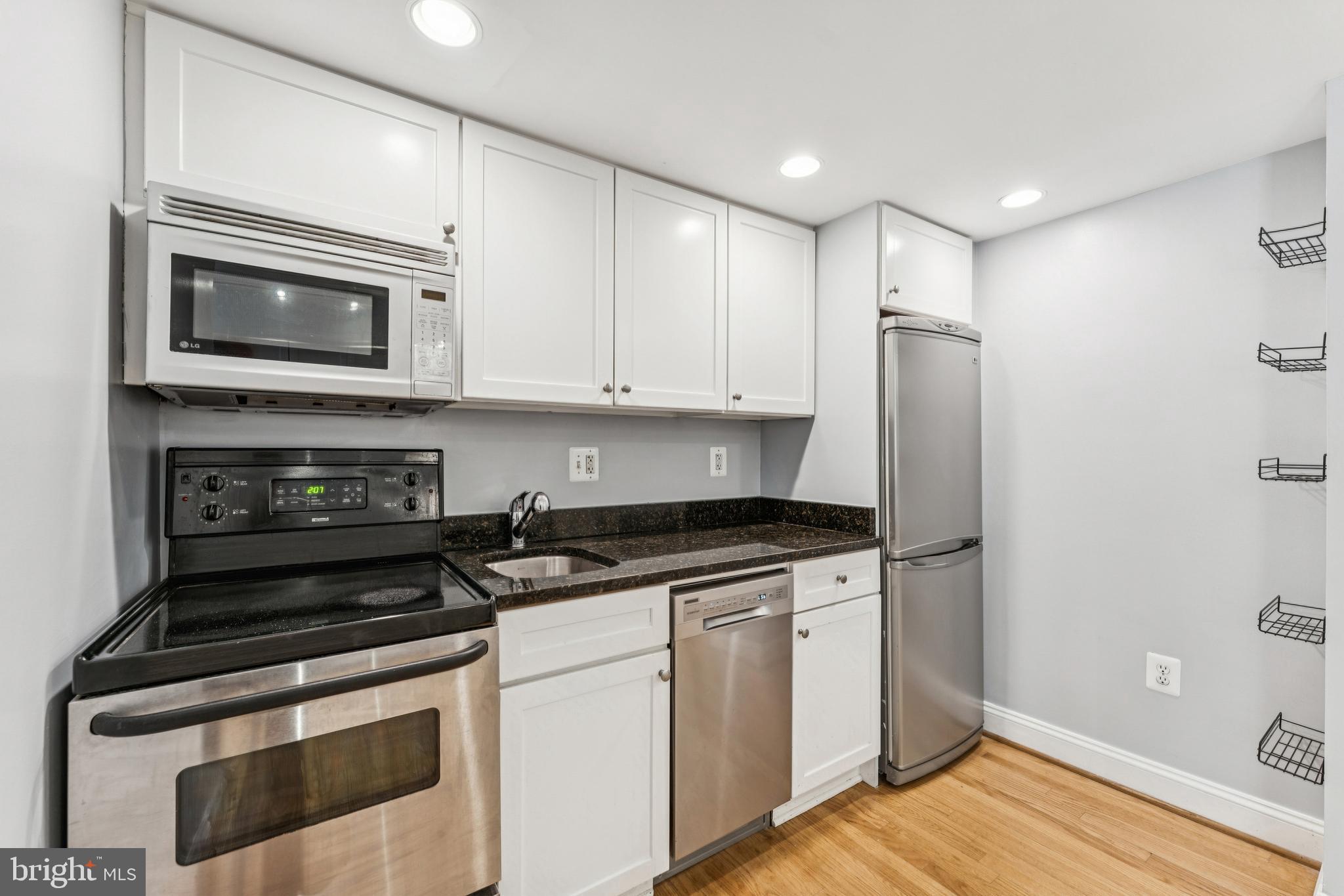 1701 16th Street Northwest, Unit 304 Washington, DC 20009 - Photo 9 of 18 a kitchen with stainless steel appliances granite countertop a stove a microwave and a refrigerator