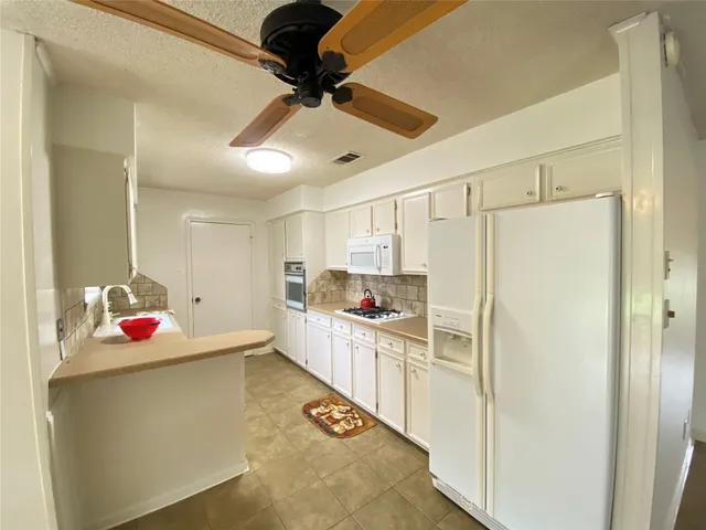 a kitchen with a refrigerator and white cabinets