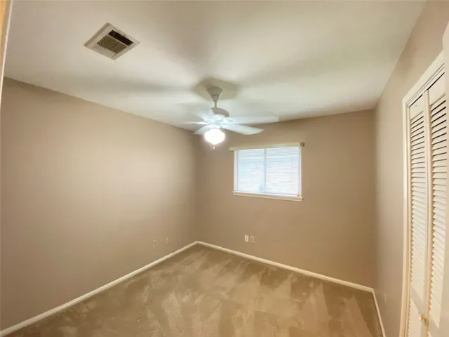 an empty room with a window and a fan