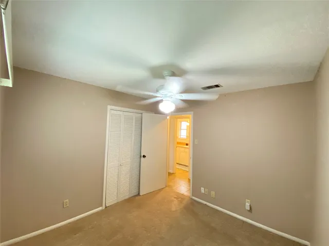 an empty room with a ceiling fan and a window