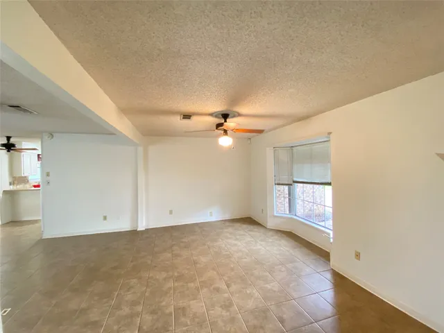 an empty room with windows and fan chandelier fan