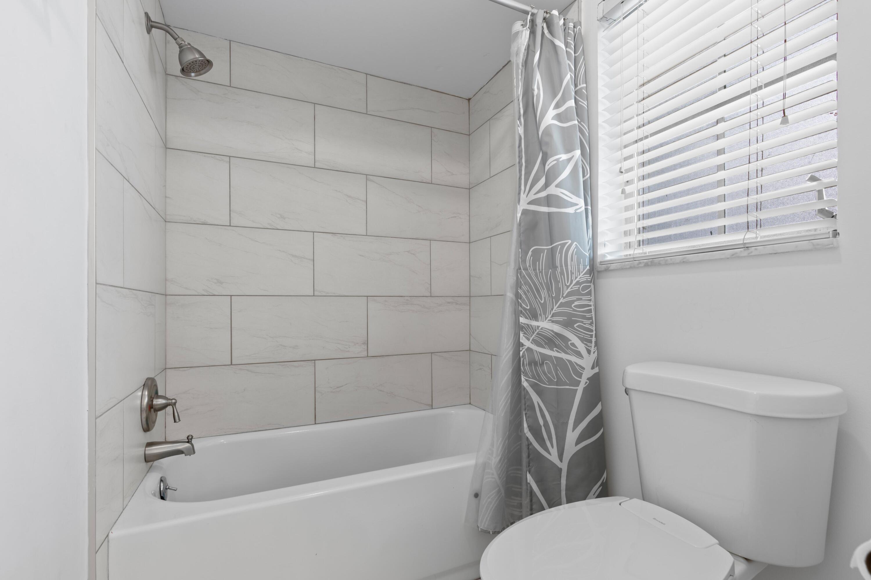 419 Pine Tree Court, Unit 21 Atlantis, FL 33462 - Photo 12 of 22 a white toilet and tub sitting next to a white sink