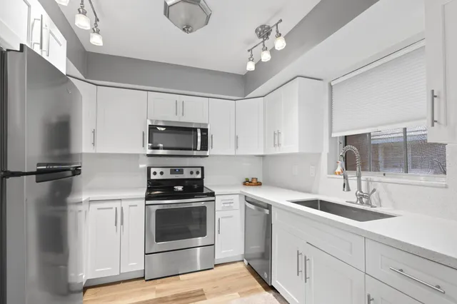 a kitchen with a sink stainless steel appliances and white cabinets