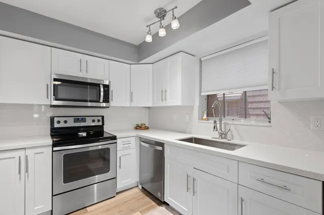 a kitchen with white cabinets appliances and a sink