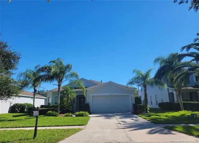 a front view of a house with a yard and palm trees