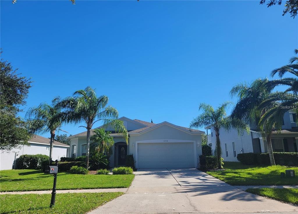 a front view of a house with a yard and palm trees
