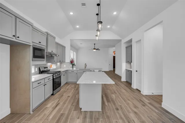 a kitchen with granite countertop a stove a sink dishwasher and a refrigerator with wooden floor