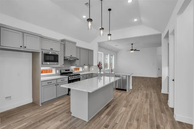 a kitchen with kitchen island white cabinets and stainless steel appliances