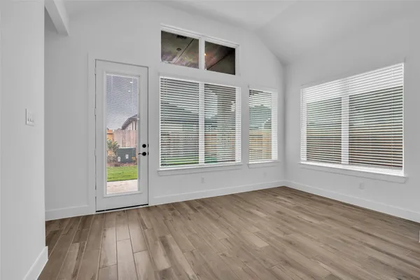 a view of an empty room with a window and wooden floor