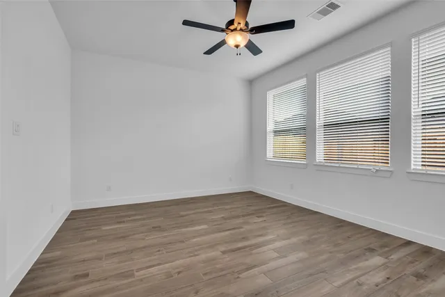 a view of empty room with wooden floor and fan