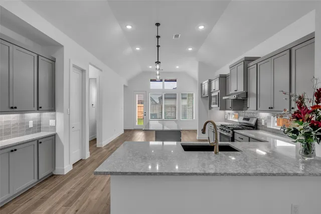 a view of a kitchen with granite countertop a large counter top appliances and cabinets