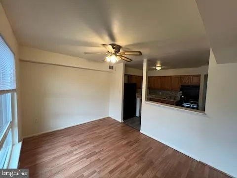 a view of a room with a ceiling fan and wooden floor
