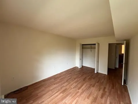 a view of an empty room with wooden floor and closet