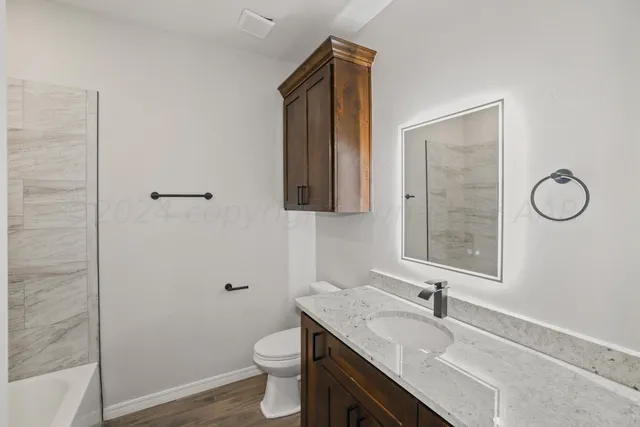 a bathroom with a granite countertop sink toilet and mirror