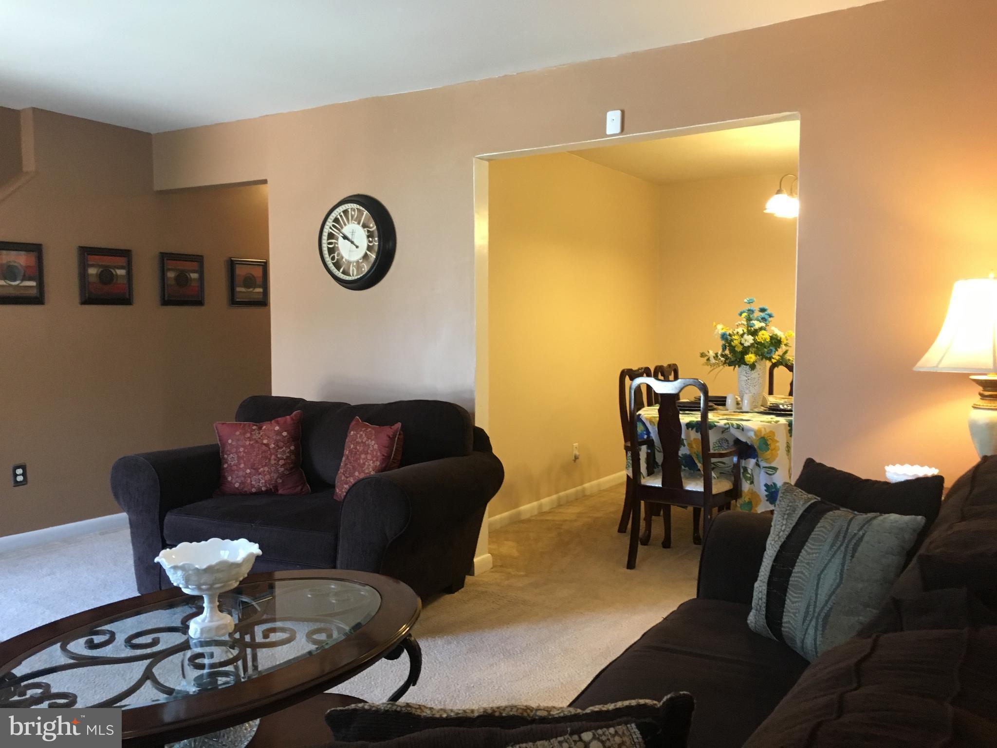 7110 Rutherford Green Circle Baltimore, MD 21244 - Photo 4 of 26 a living room with furniture a clock on wall and a table