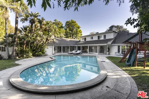 a view of a house with swimming pool and next to a yard