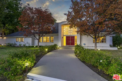 a front view of a house with a yard and trees