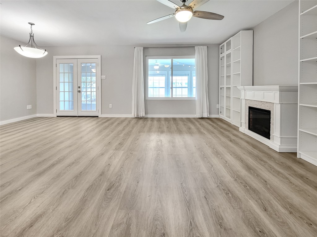 an empty room with wooden floor fan and windows