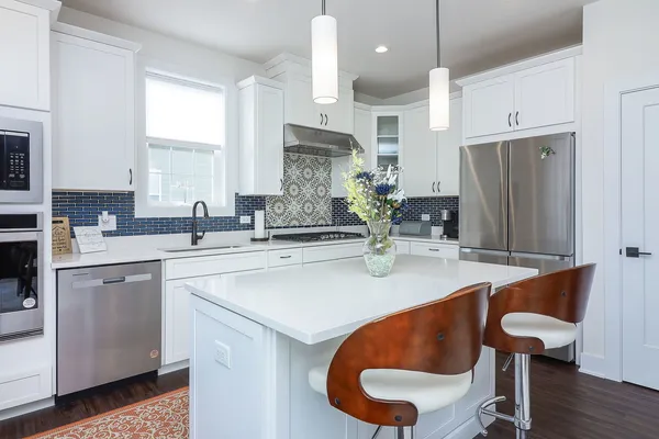 a kitchen with stainless steel appliances granite countertop a sink a stove a refrigerator and island with wooden floor
