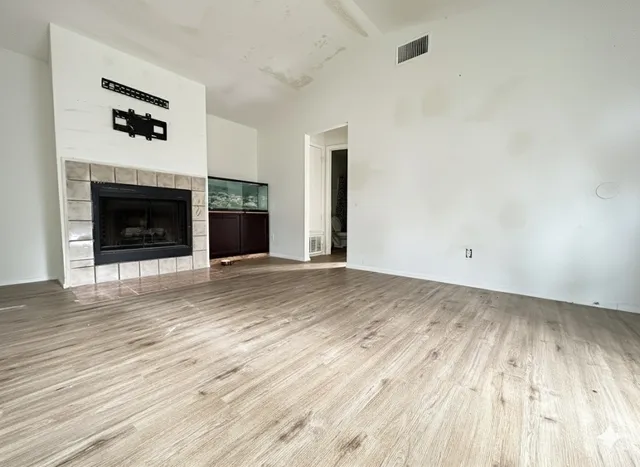 an empty room with wooden floor and fireplace