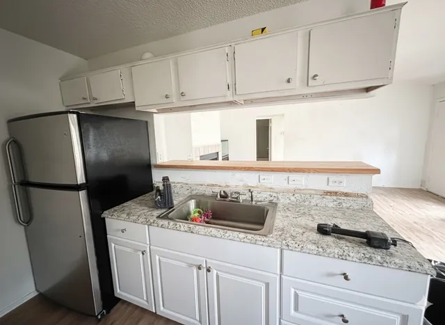 a kitchen with granite countertop a refrigerator sink and cabinets