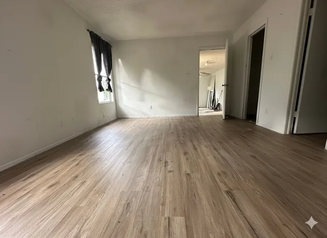 an empty room with wooden floor and windows